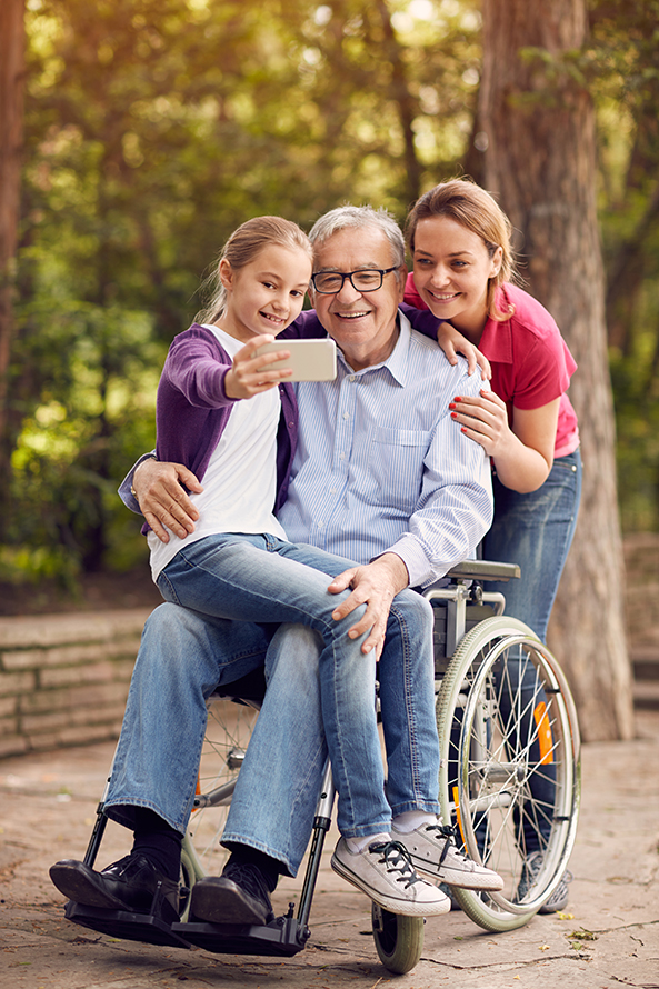 senior in wheelchair taking selfies with children